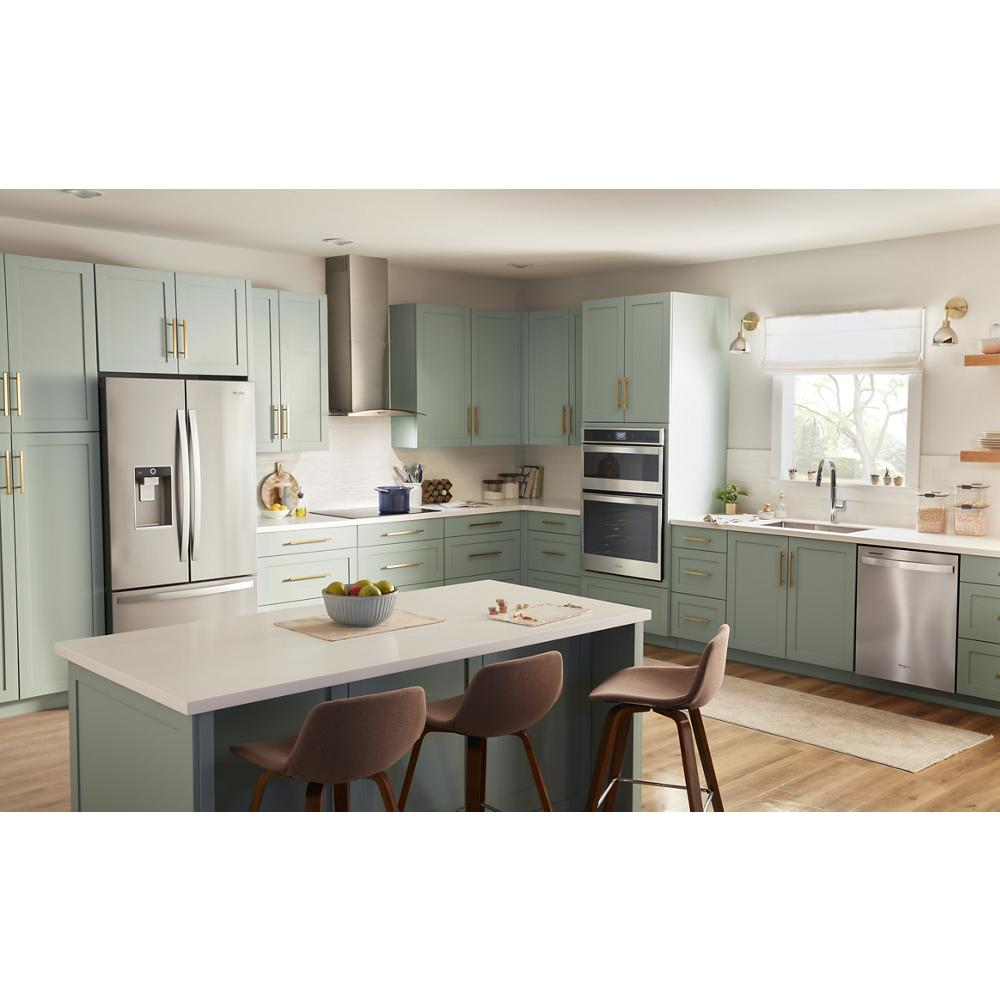 Bright kitchen with sage green cabinets, stainless steel appliances, and a central island with brown stools in modern home