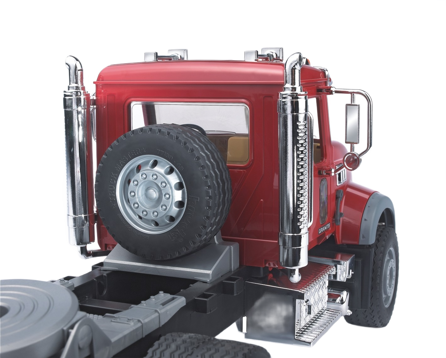 Red truck cab with spare tire mounted behind the driver’s seat, featuring chrome exhaust stacks and detailed accents
