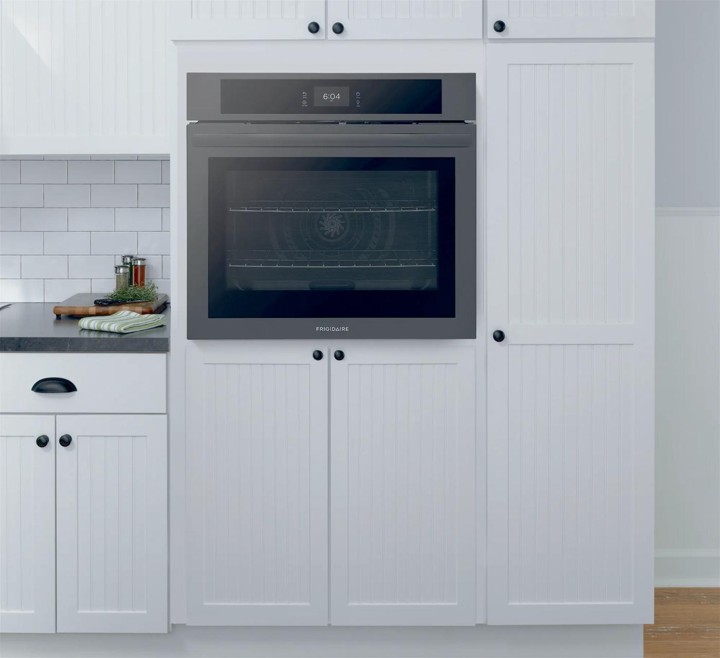 Built-in modern wall oven with fan convection and digital controls integrated into white kitchen cabinetry setting