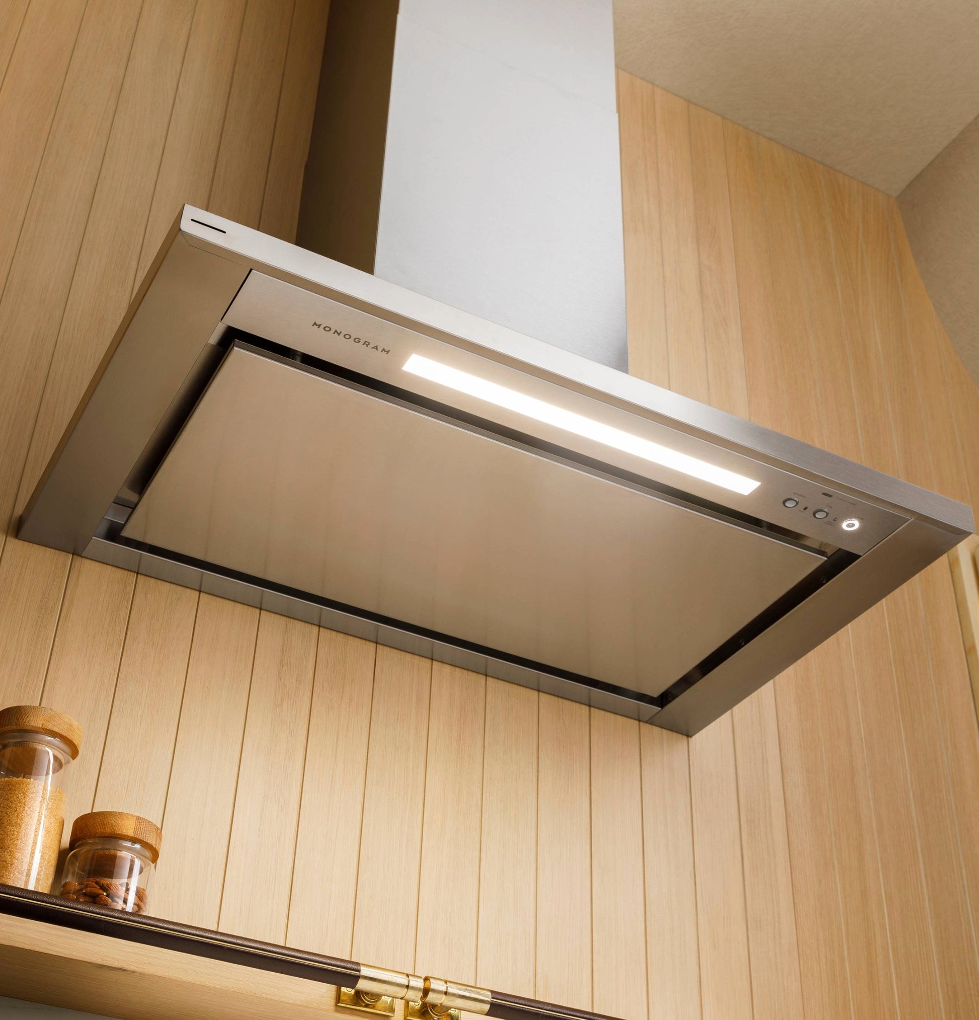 Sleek stainless steel wall-mounted pyramid chimney vent hood with integrated lighting in modern kitchen appliances collection
