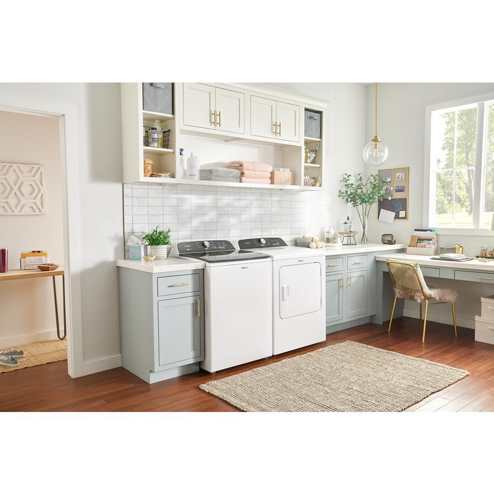 Laundry room with white gas dryer and washer under white and light gray cabinetry on hardwood floors