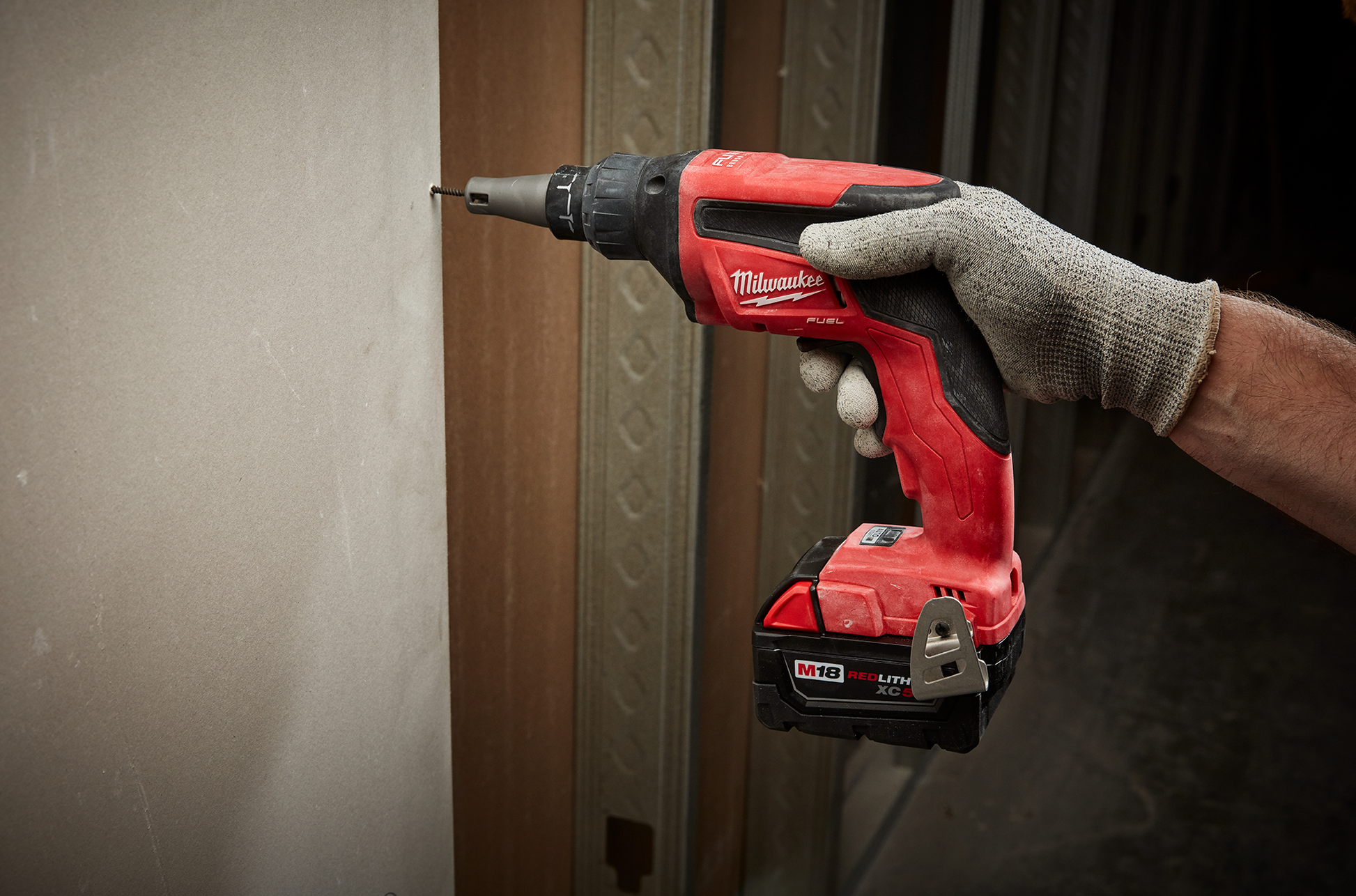 Person using red cordless drywall screw gun in a woodworking project from hand tools and home improvement collections