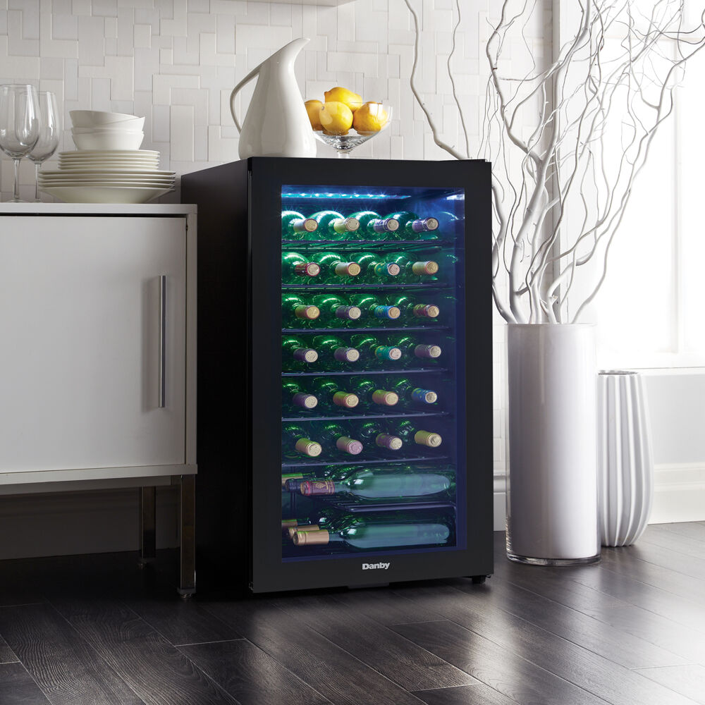Free-standing wine cooler with glass door, illuminated blue LED interior, and multiple wire racks storing wine bottles