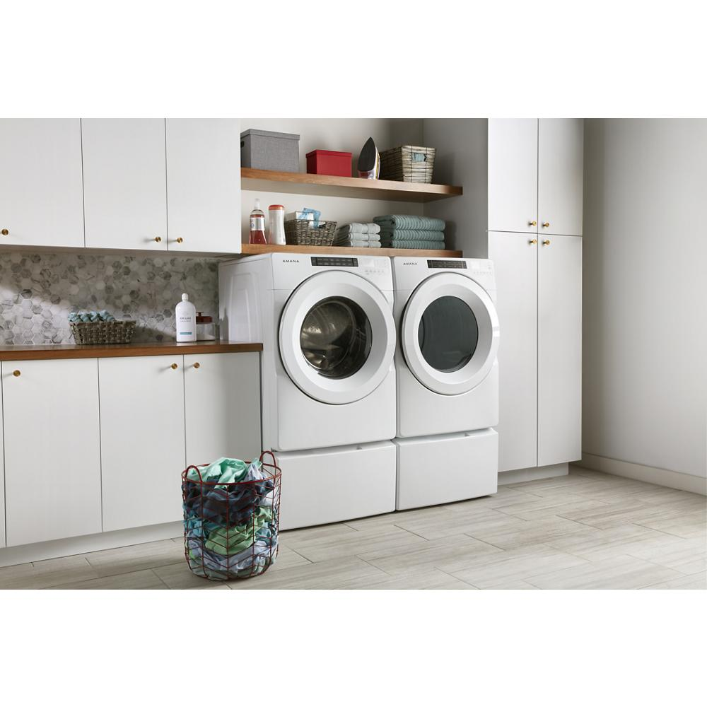 Laundry room with white front-load washer and dryer elevated on pedestals with storage drawers in modern appliance setting