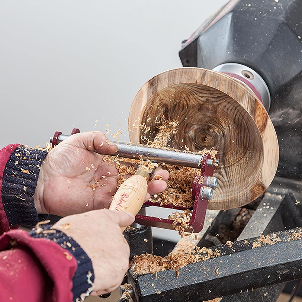 Hands using a chisel on a wooden bowl secured by the Sorby SteadyPro Turning System during woodturning work