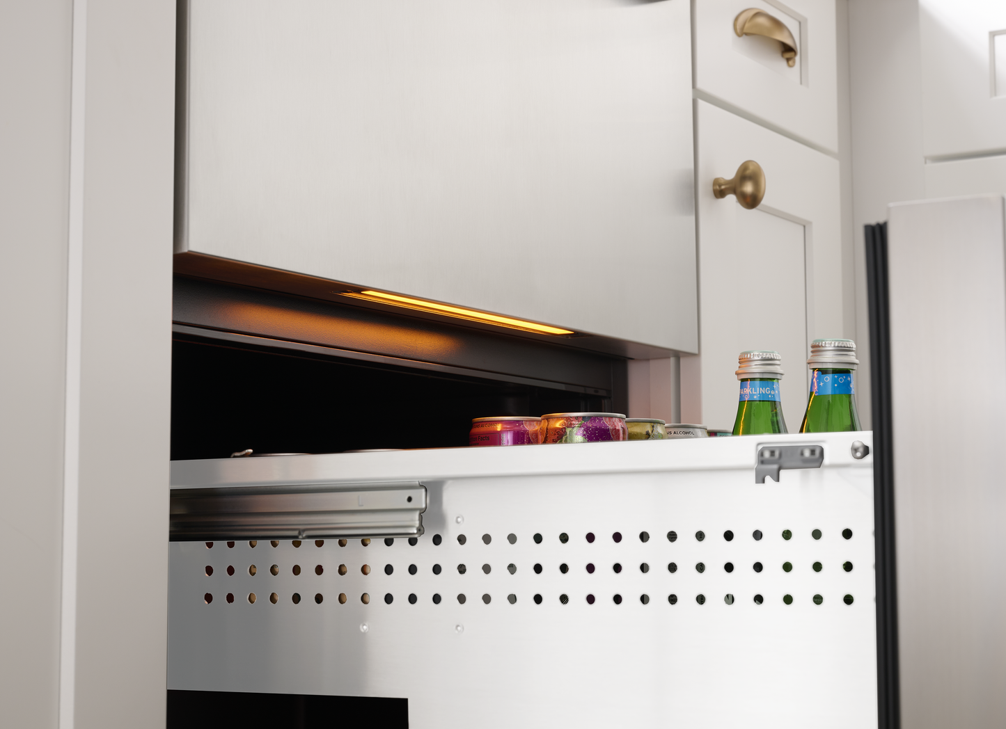 Under-counter stainless steel single zone refrigerator drawer partially open with beverages inside in kitchen setting