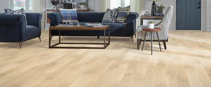 Spacious living room featuring light wood flooring, a dark blue sofa, patterned cushions, a striped armchair, and modern decor with natural light.