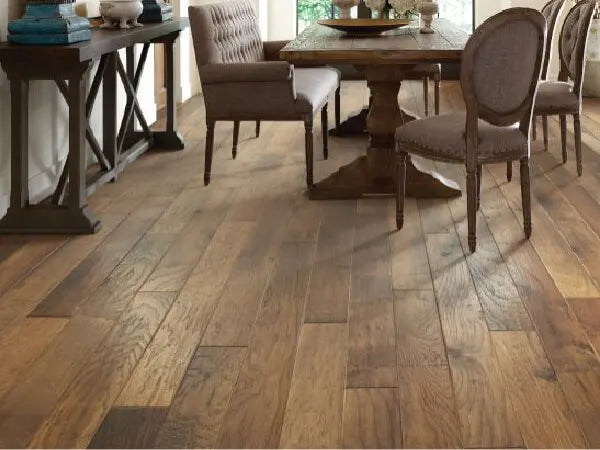 Dining room with medium-toned hardwood flooring, featuring a wooden table, upholstered chairs, and a side console with decorative items.