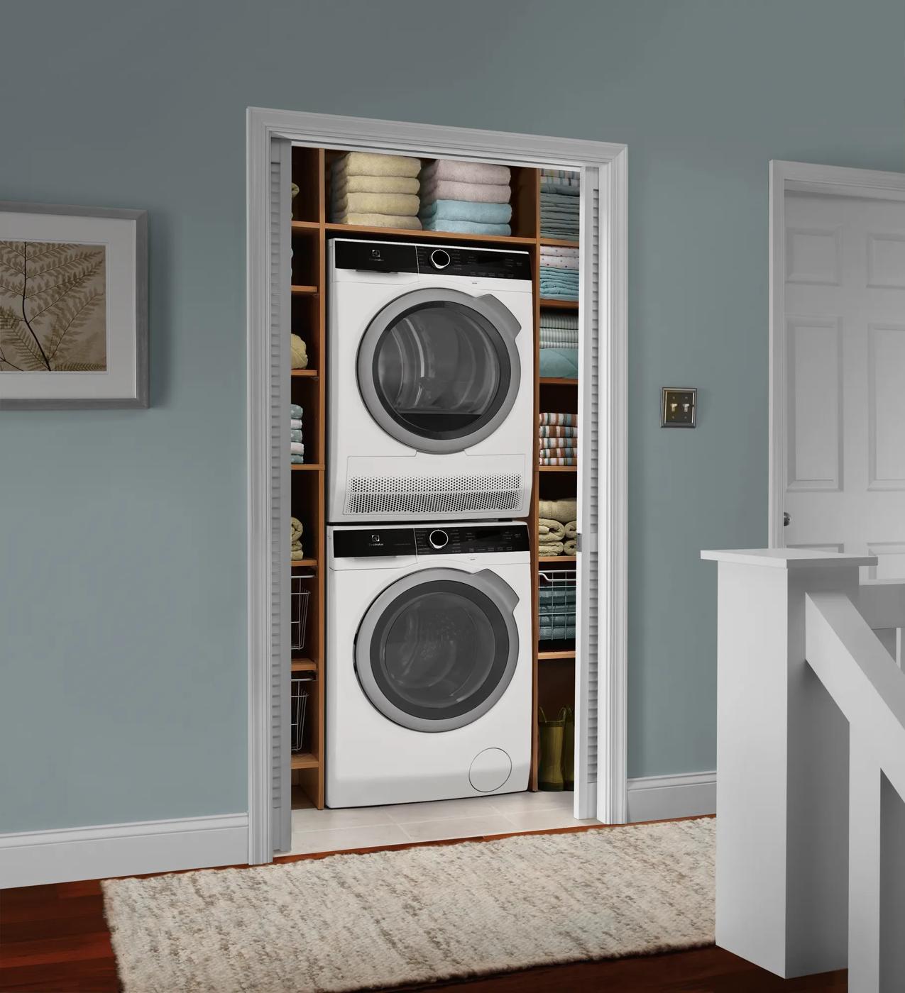 Stacked white front load washer and compact ventless dryer in a laundry closet with organized shelving in home appliances collection