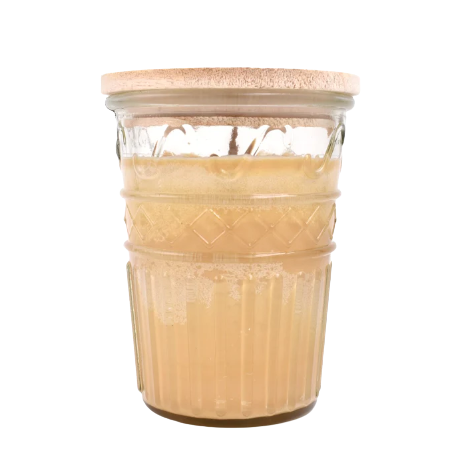Amber-toned candle in textured glass jar with natural wood lid for home fragrance and decor