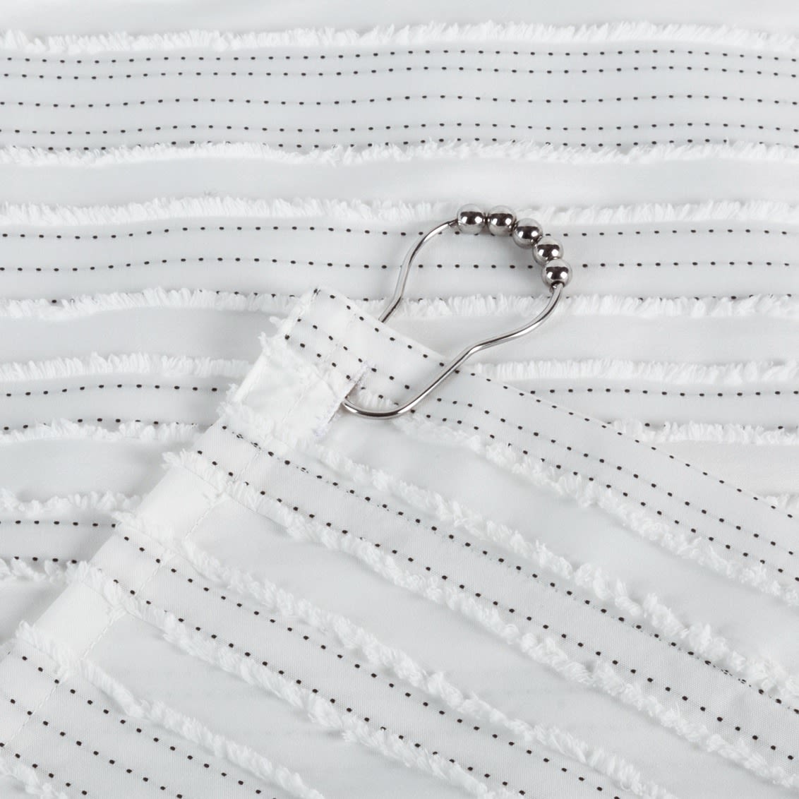 Close-up of white polyester shower curtain with delicate dotted backstitch and metal ball shower ring in bathroom accessories
