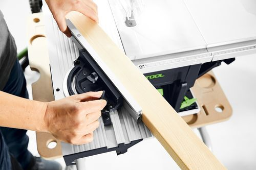 Person adjusting the fence on a Festool cordless table saw while positioning a wood board for a precise rip cut