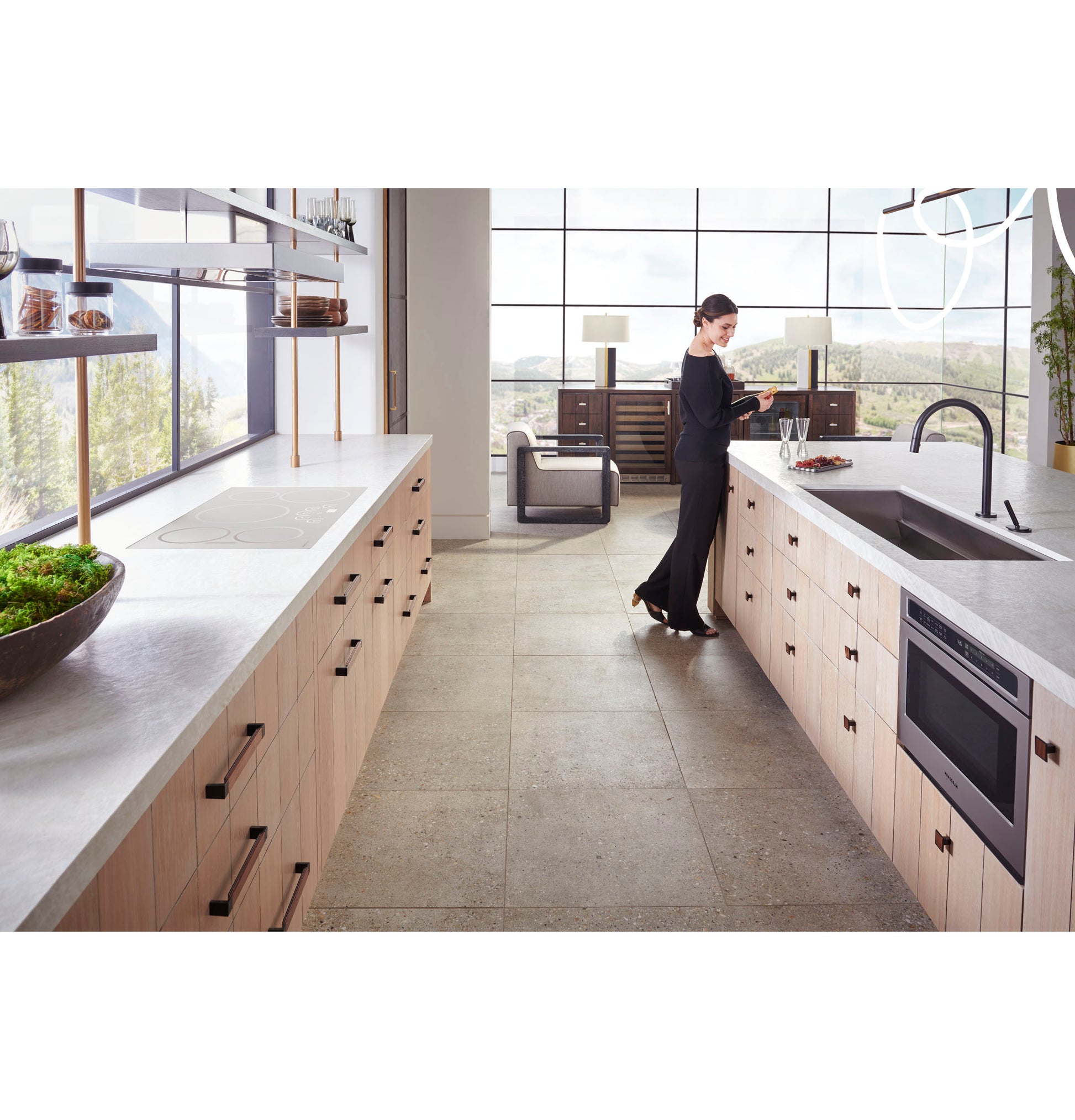 Modern kitchen with light wood cabinetry features built-in stainless steel microwave drawer and spacious concrete countertops