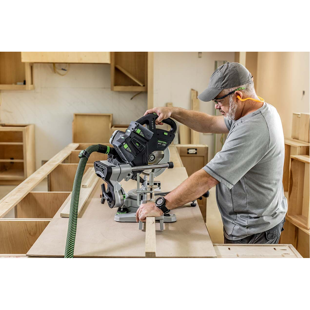 Man using Festool cordless compound miter saw in a woodworking workshop with safety ear protection and dust extraction hose
