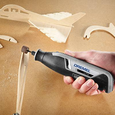 Compact rotary tool with sanding attachment shaping wooden model parts for detailed home improvement tasks