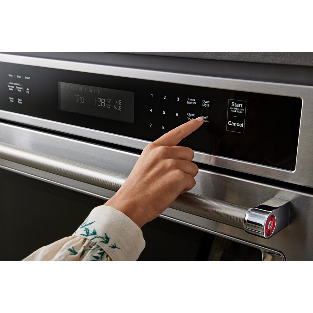 User finger pressing digital control panel on stainless steel single wall oven from KitchenAid appliances