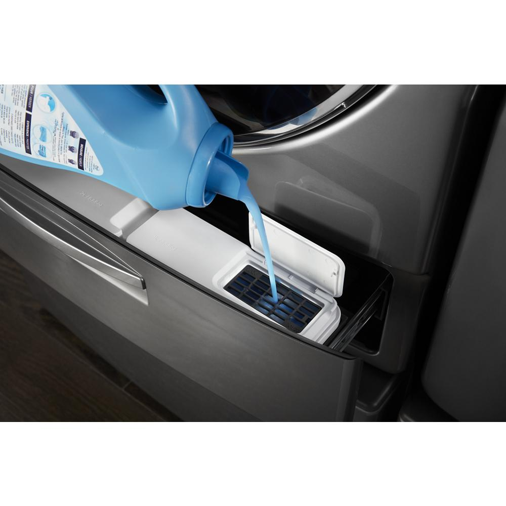 Liquid detergent being poured into detergent compartment of a modern metallic front load washer in appliances collection