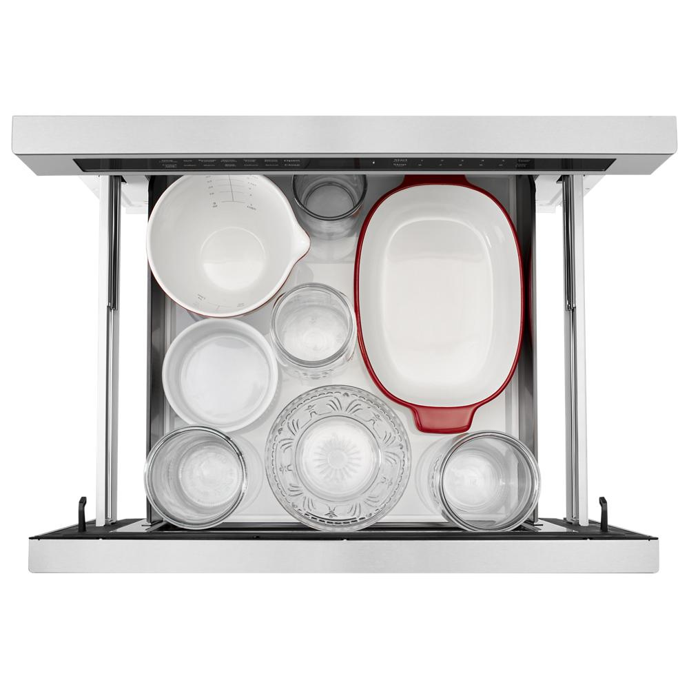 Open stainless steel under-counter microwave drawer showing multiple bowls and glass containers inside from KitchenAid collection