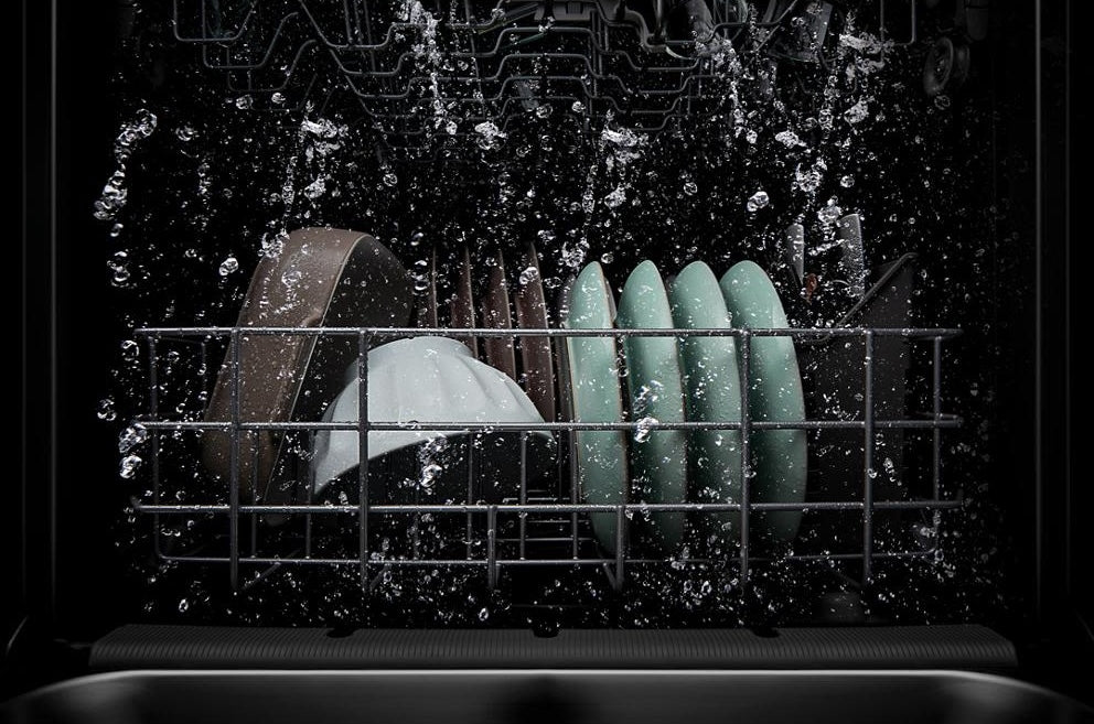 Inside view of dishwasher rack with clean dishes and water spray during wash cycle in kitchen appliances collection