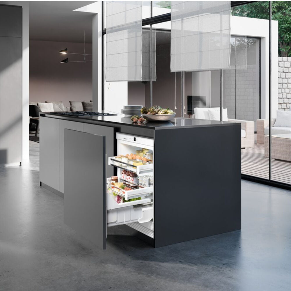 Modern kitchen island with open undercounter refrigerator drawer showing organized fresh food storage