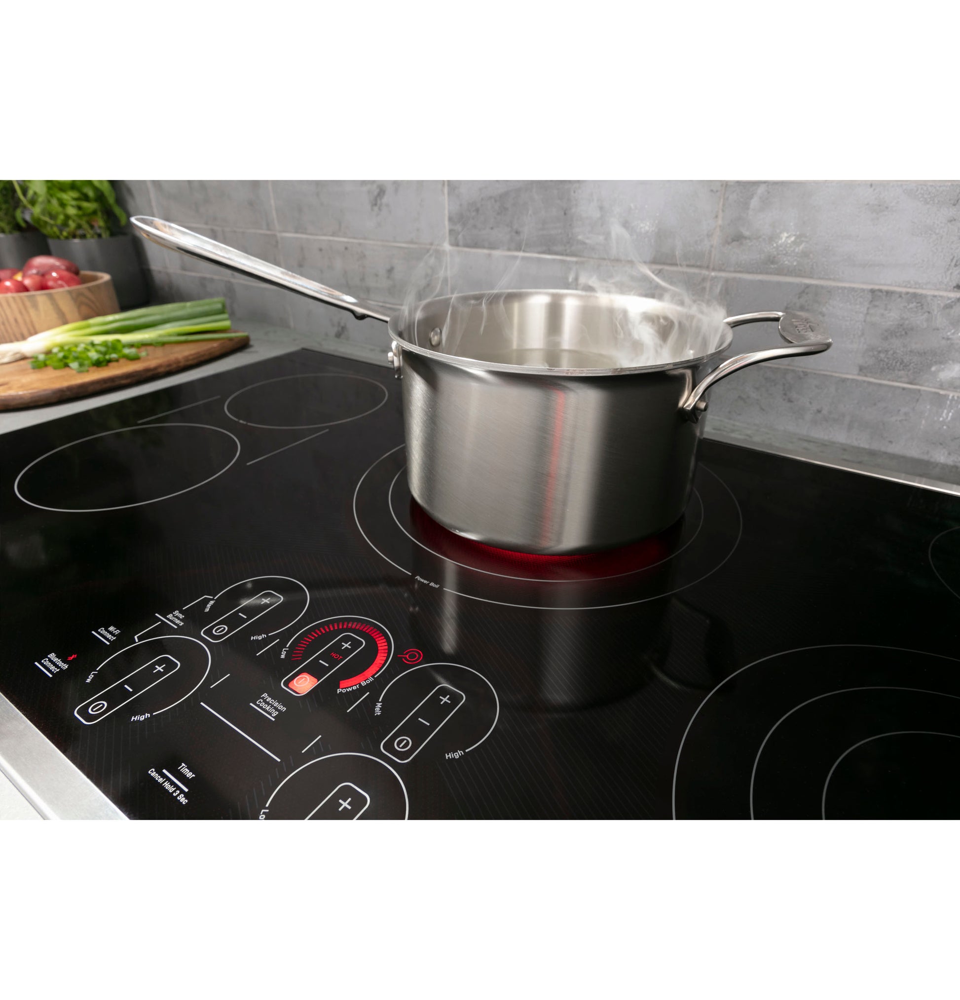 Stainless steel pot boiling on black built-in touch control electric cooktop in modern kitchen setting