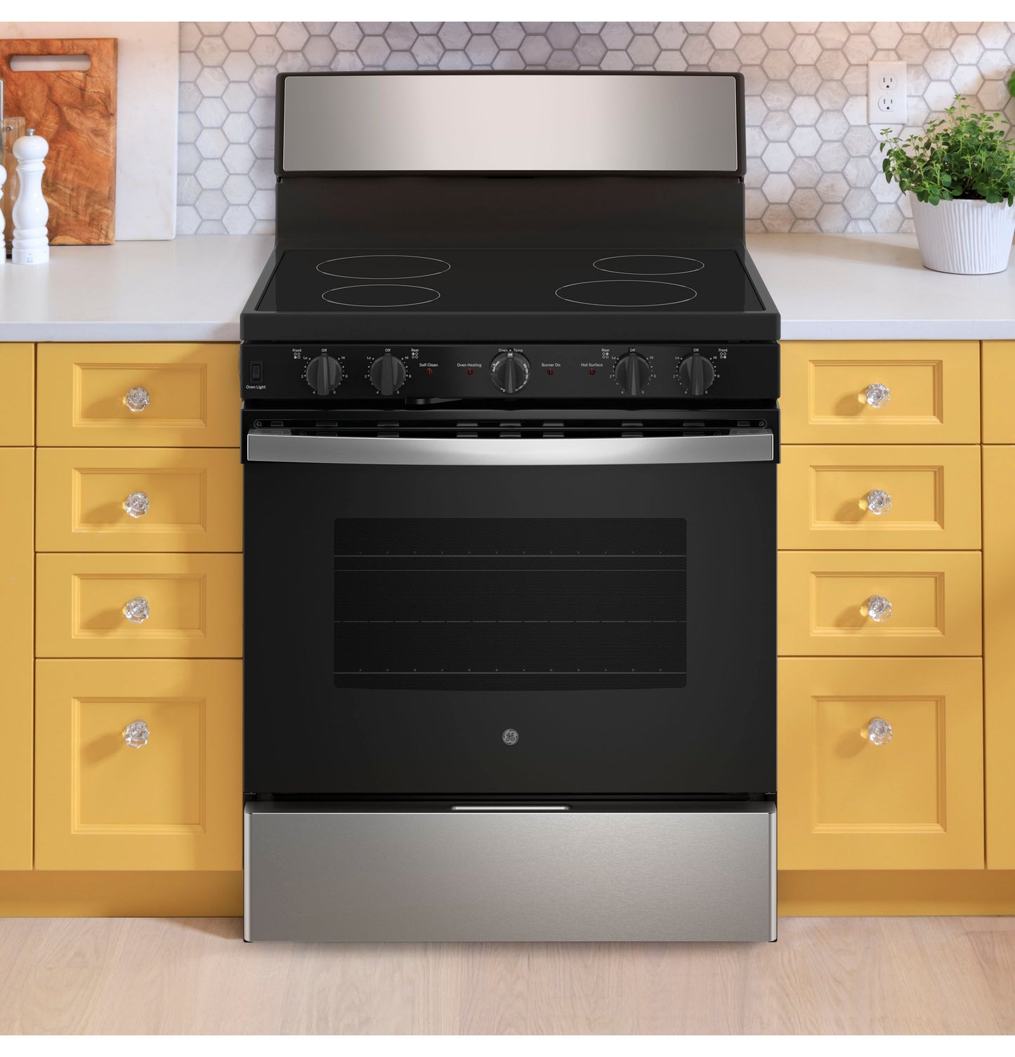 Black and stainless steel electric radiant smooth cooktop range surrounded by yellow kitchen drawers and countertops