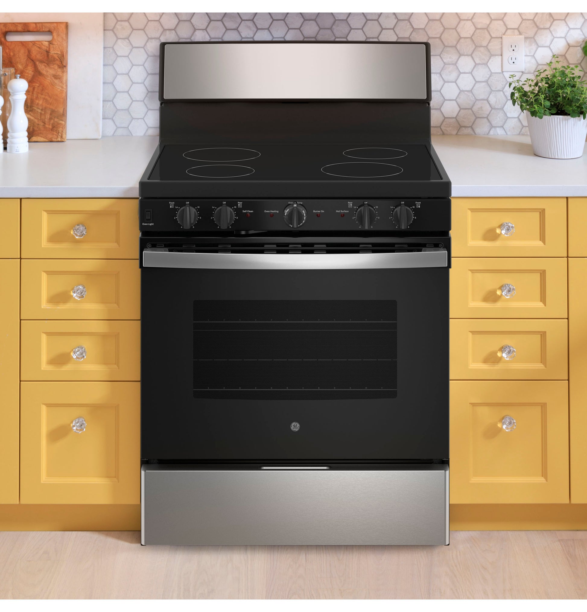 Black and stainless steel electric radiant smooth cooktop range surrounded by yellow kitchen drawers and countertops