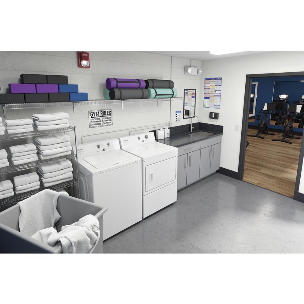 Laundry room with commercial top-load washer, dryer, folded towels, mats, and entry to fitness area with equipment.