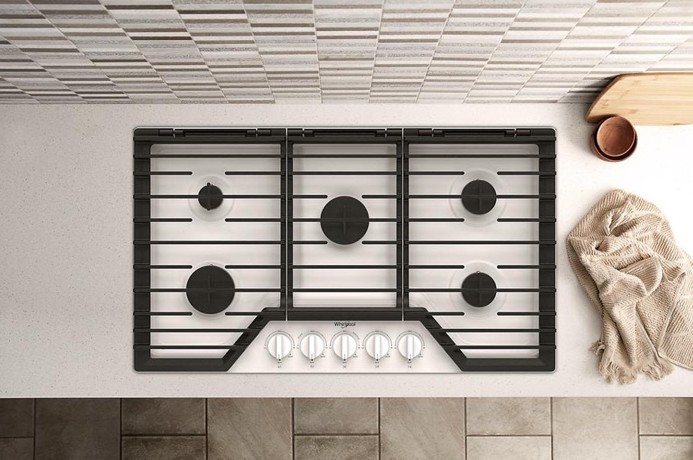 36-inch gas cooktop with five burners and hinged cast-iron grates on a light kitchen countertop for home improvement