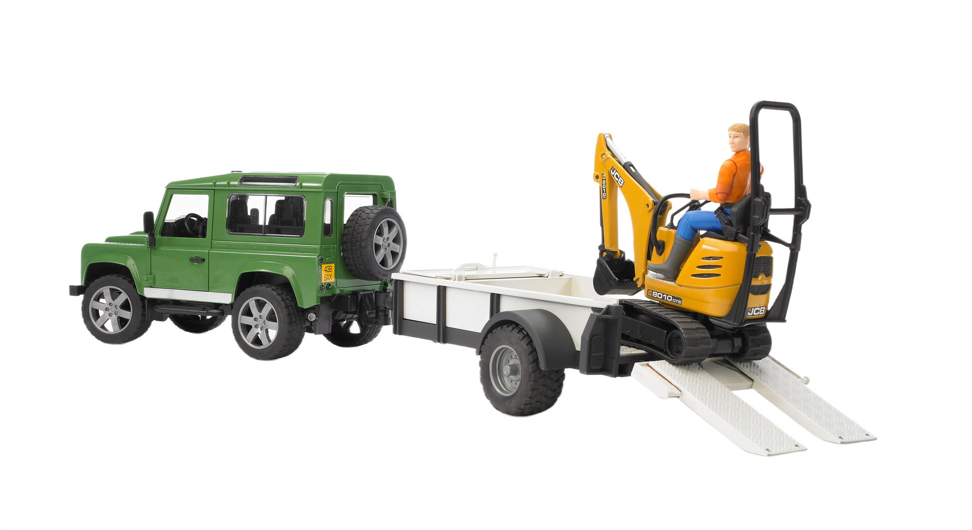 Green off-road vehicle towing white trailer carrying detailed yellow JCB micro excavator toy from Bruder Toys collection
