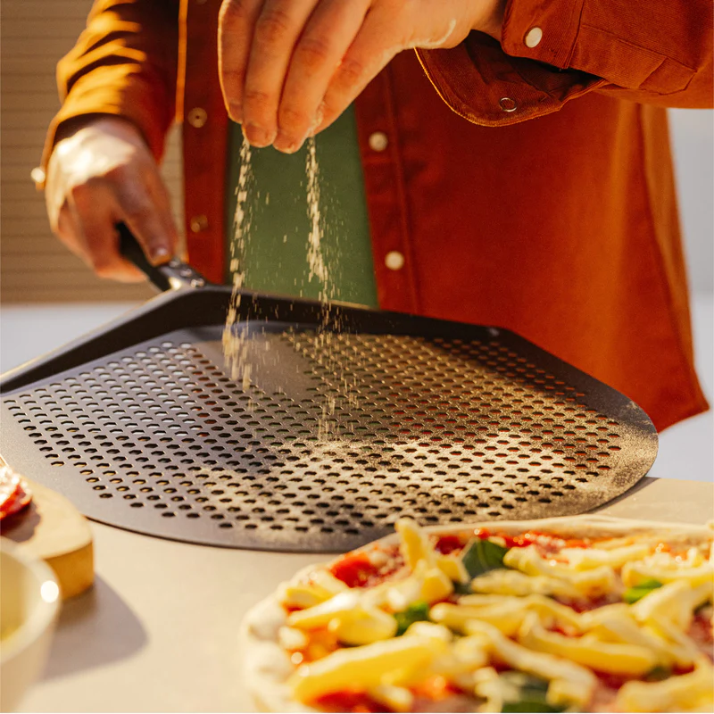 Perforated pizza peel with black handle used in outdoor grilling and accessories for pizza preparation and outdoor living