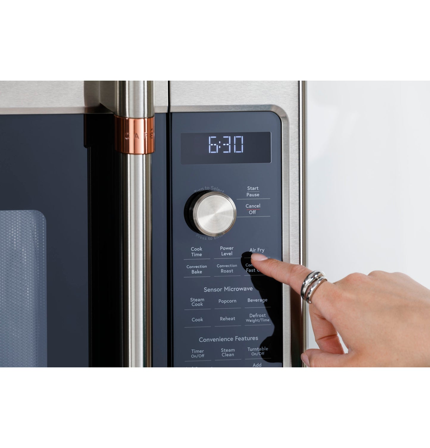 Close-up of hand pressing control dial on stainless steel convection microwave oven panel with digital timer display