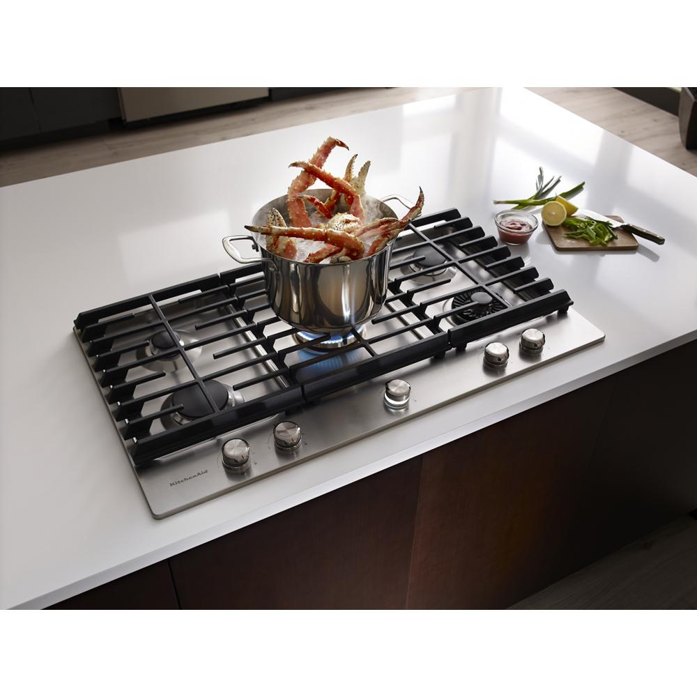 Stainless steel cooktop with five burners and pot cooking crab legs on white kitchen counter in KitchenAid collection