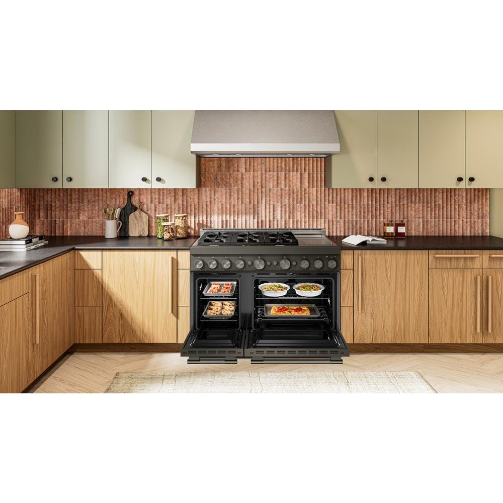 Modern kitchen with open double oven cooking multiple dishes and 6-burner commercial-style gas range with griddle