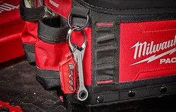 Red metal multi-bit mini ratchet keychain attached to Milwaukee tool bag for home improvement tasks
