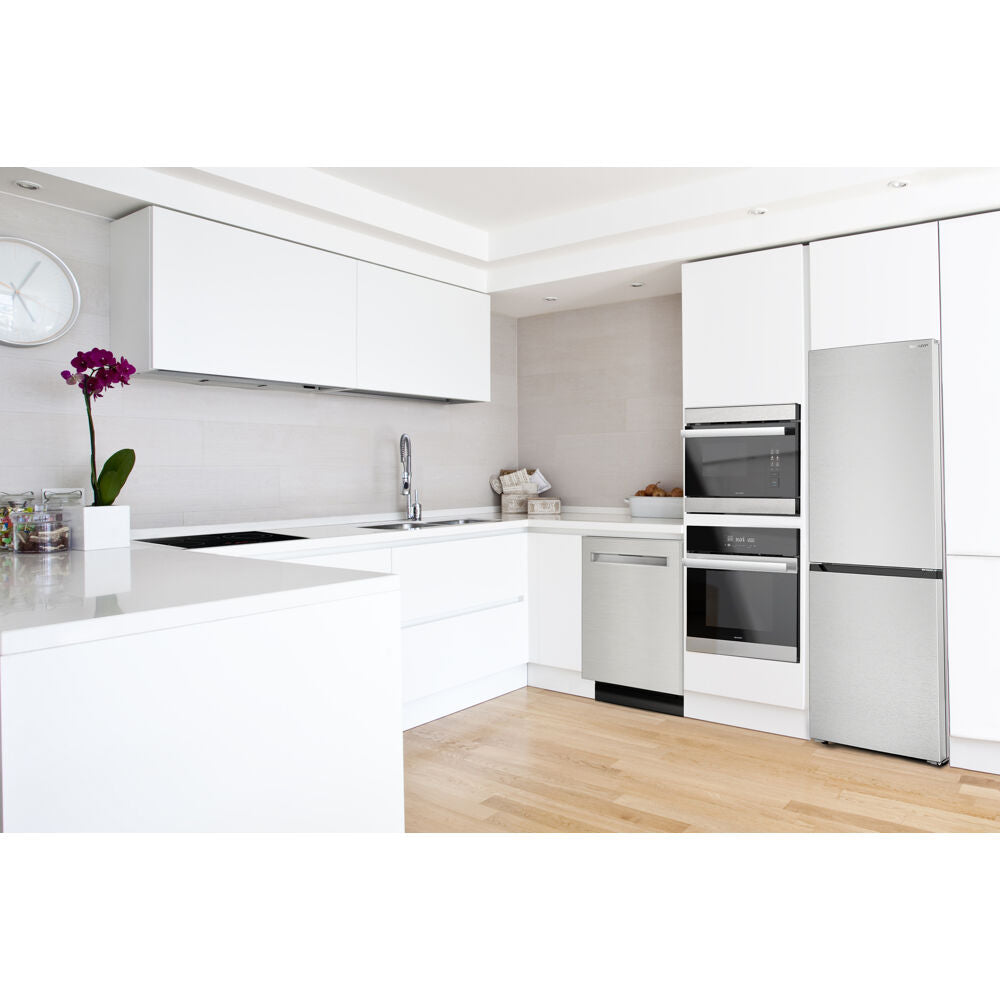 Modern white kitchen featuring a built-in double wall oven, stainless steel refrigerator, and sleek cabinetry in a bright space