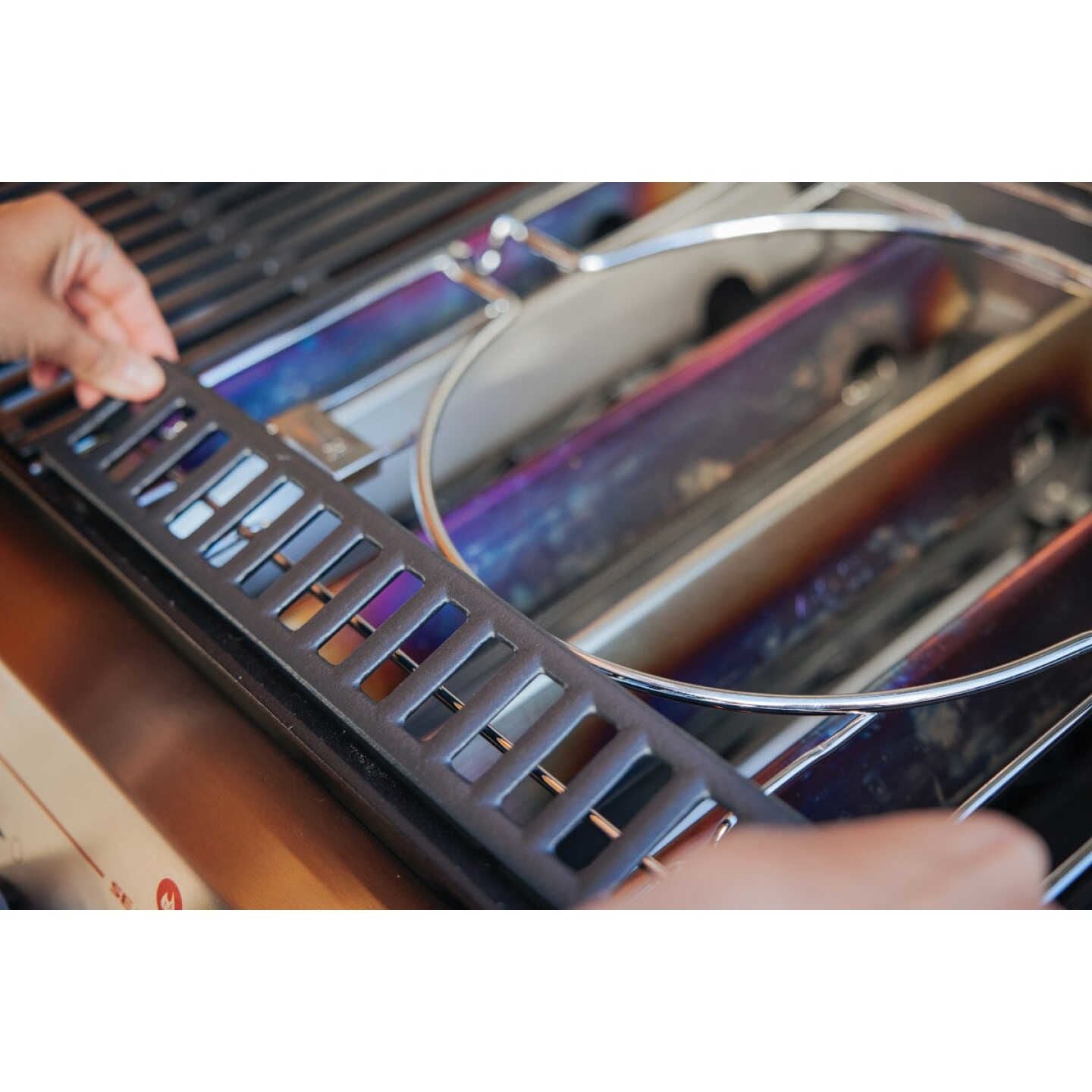 Person installing plated steel grill grate frame with porcelain-enameled spacer in outdoor grill accessory setup