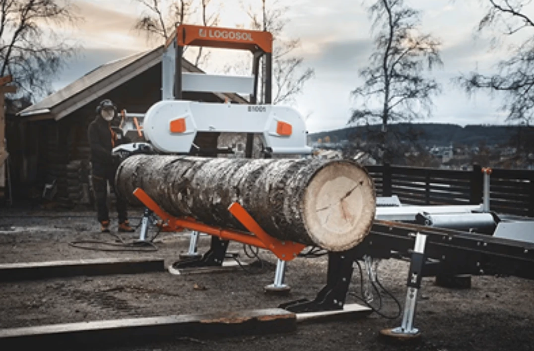 Heavy-duty log loader with dual lifting arms positioning large log on sawmill in outdoor tool accessories setting