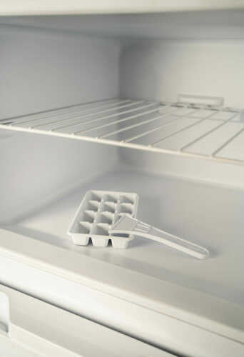 Interior view of a top mount refrigerator with adjustable glass shelving and ice cube tray on bottom shelf