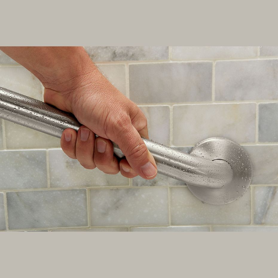 Hand gripping stainless steel concealed screw grab bar installed on bathroom tiled wall for safety and accessibility