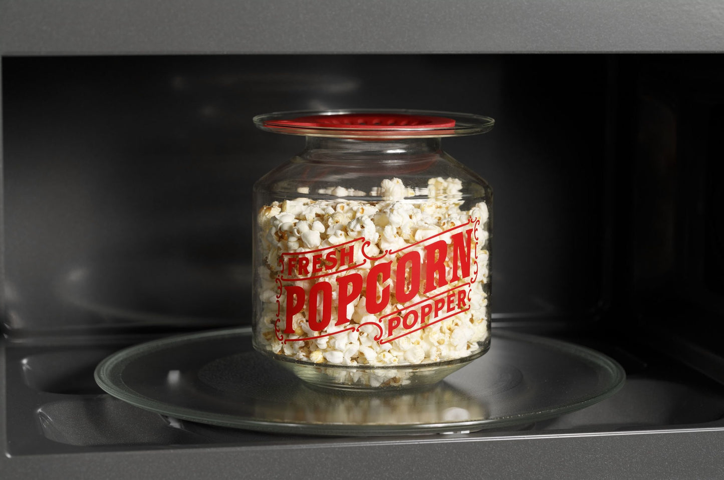 Glass jar labeled fresh popcorn popper filled with popped corn inside microwave from kitchen appliances collection
