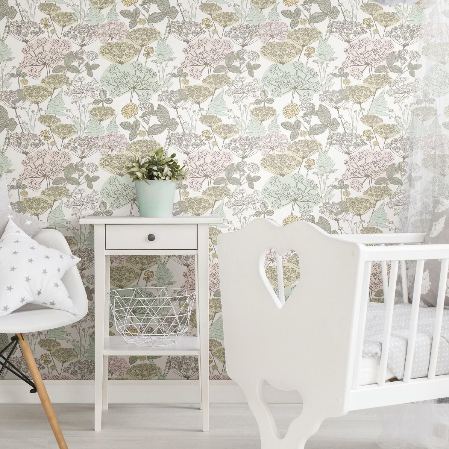 Peel and stick wallpaper with soft pink and green floral print in a nursery setting with white furniture and decor