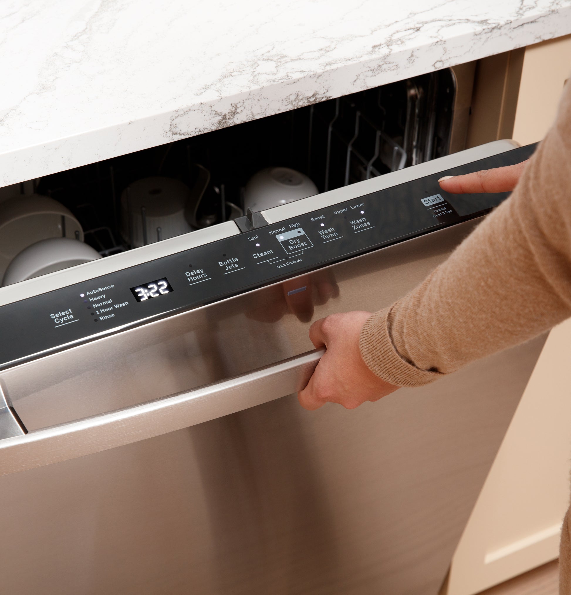 User pressing a control panel button on a stainless steel dishwasher integrated into a modern kitchen counter