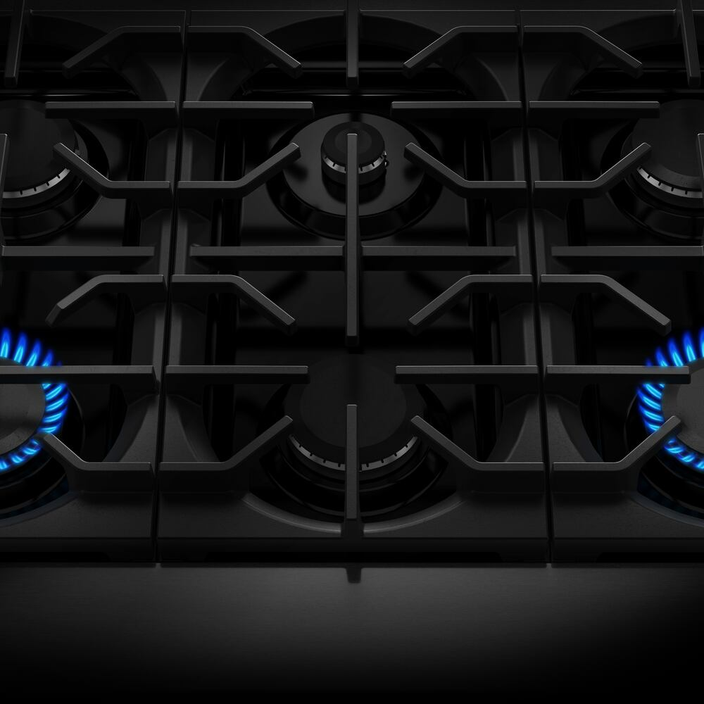 Close-up of black six-burner gas cooktop with two burners ignited from KitchenAid ranges collection