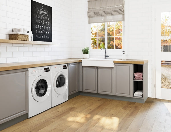 Laundry room with gray cabinets, wooden countertop, white washer and dryer, farmhouse sink, and bright window view