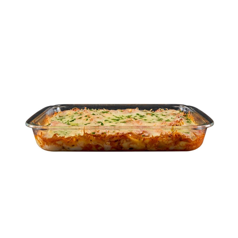 Glass baking dish filled with golden baked casserole topped with melted cheese and sprinkled herbs on white background