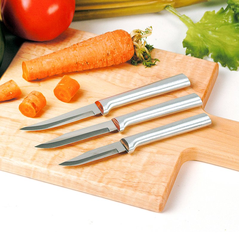 Three sharp paring knives with satin-finish metal handles on wooden cutting board with sliced carrot in kitchenware collections