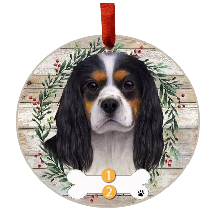 Round Christmas ornament featuring a tri-color King Charles dog face wreath with red ribbon for hanging