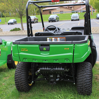 Rear view of green utility vehicle with 4x4 drivetrain and rugged Terra-Hawk tires on grassy terrain