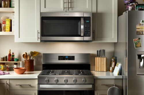 Kitchen featuring a stainless steel Whirlpool microwave with sensor cooking installed above a gas range and light cabinetry